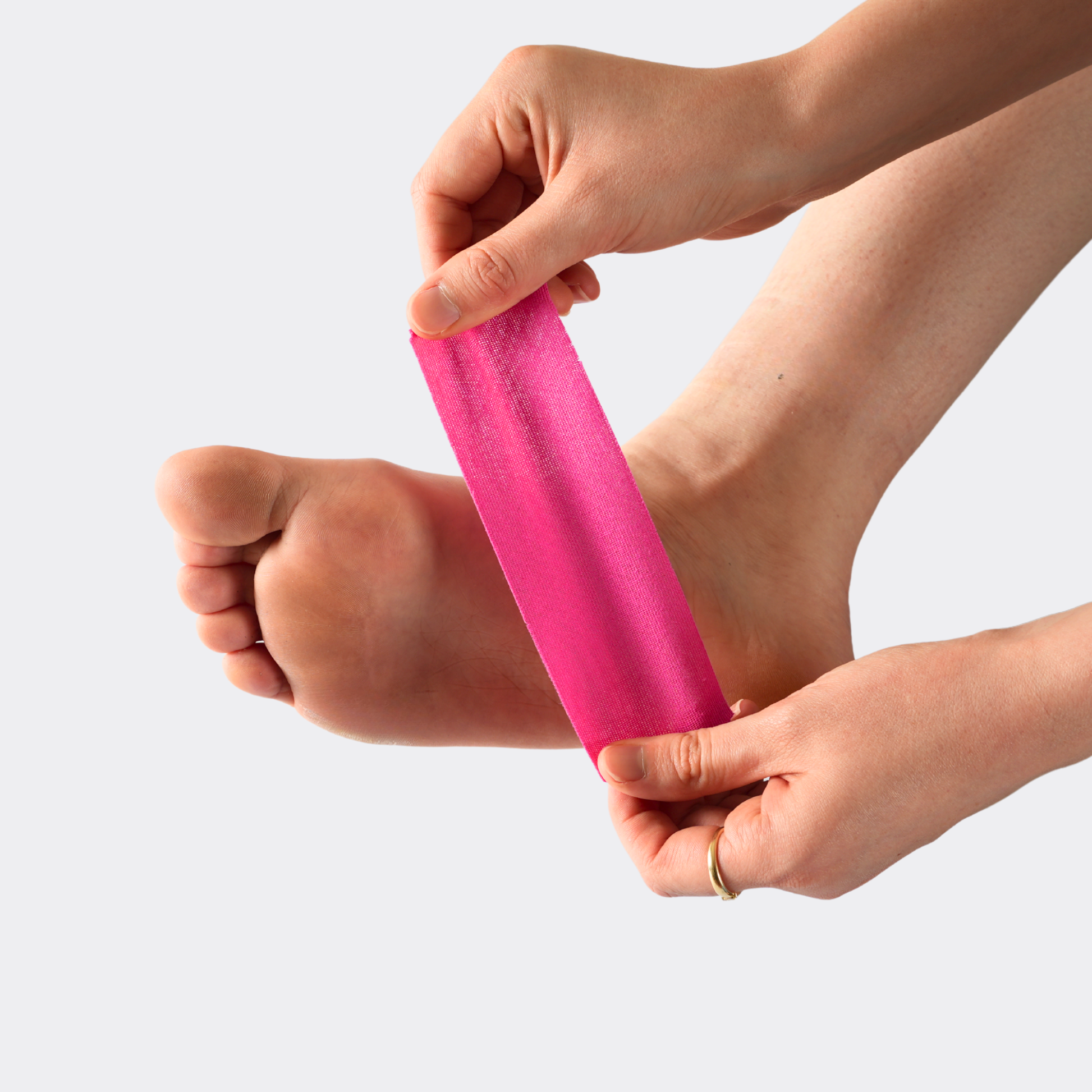 Person using a pink resistance band on their foot against a light gray background