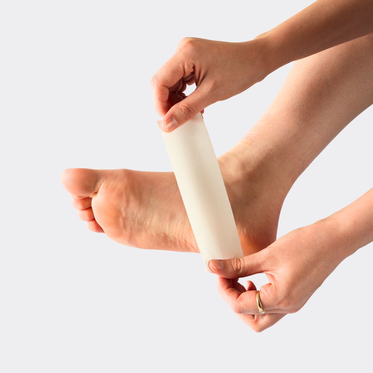 Person applying a white stick to their foot against a light gray background