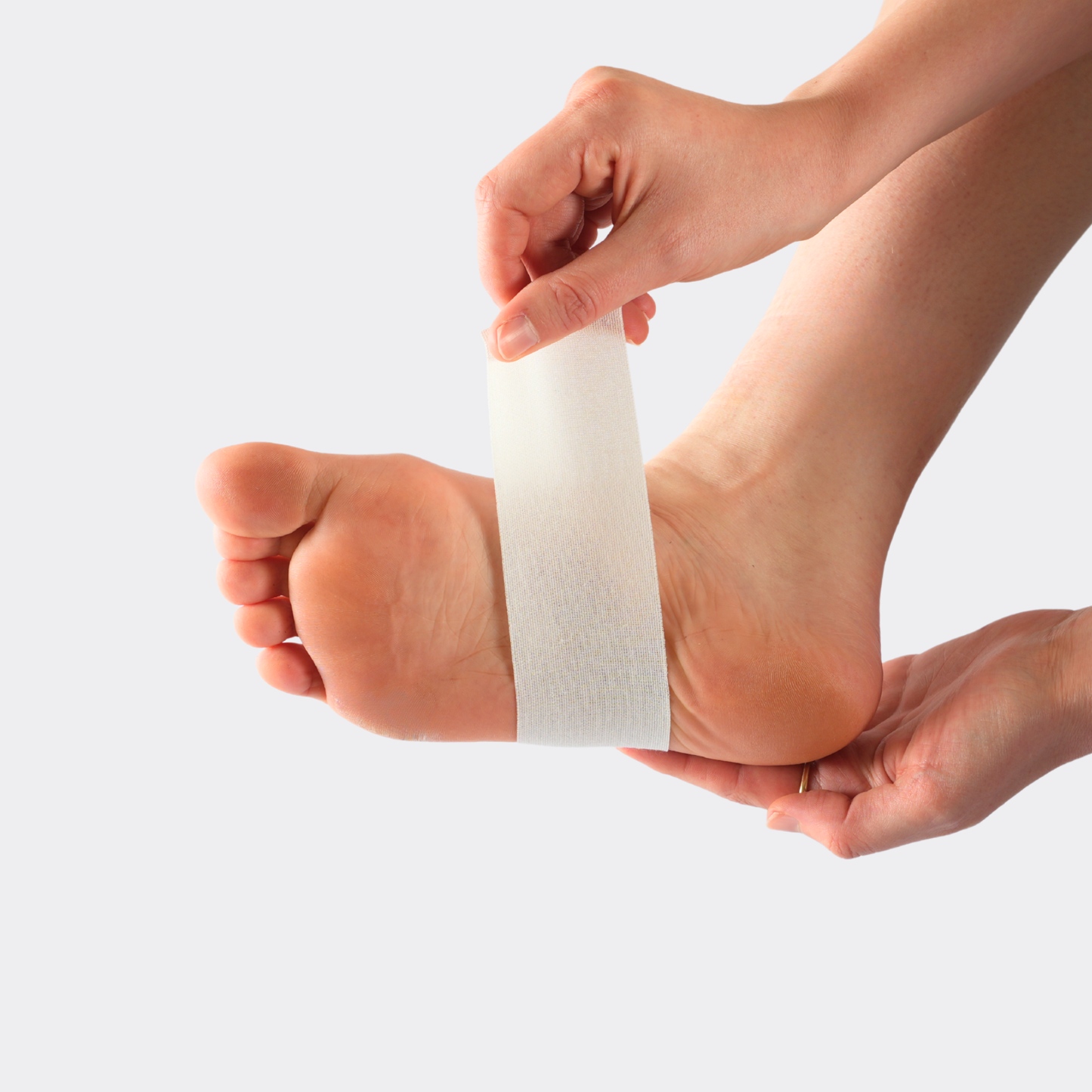 Person applying white bandage to a foot on a light gray background